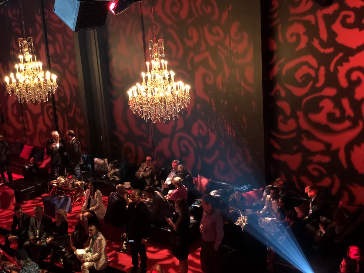 Salle de cabaret aux lustres de cristal, murs habillés de gobos rouges
