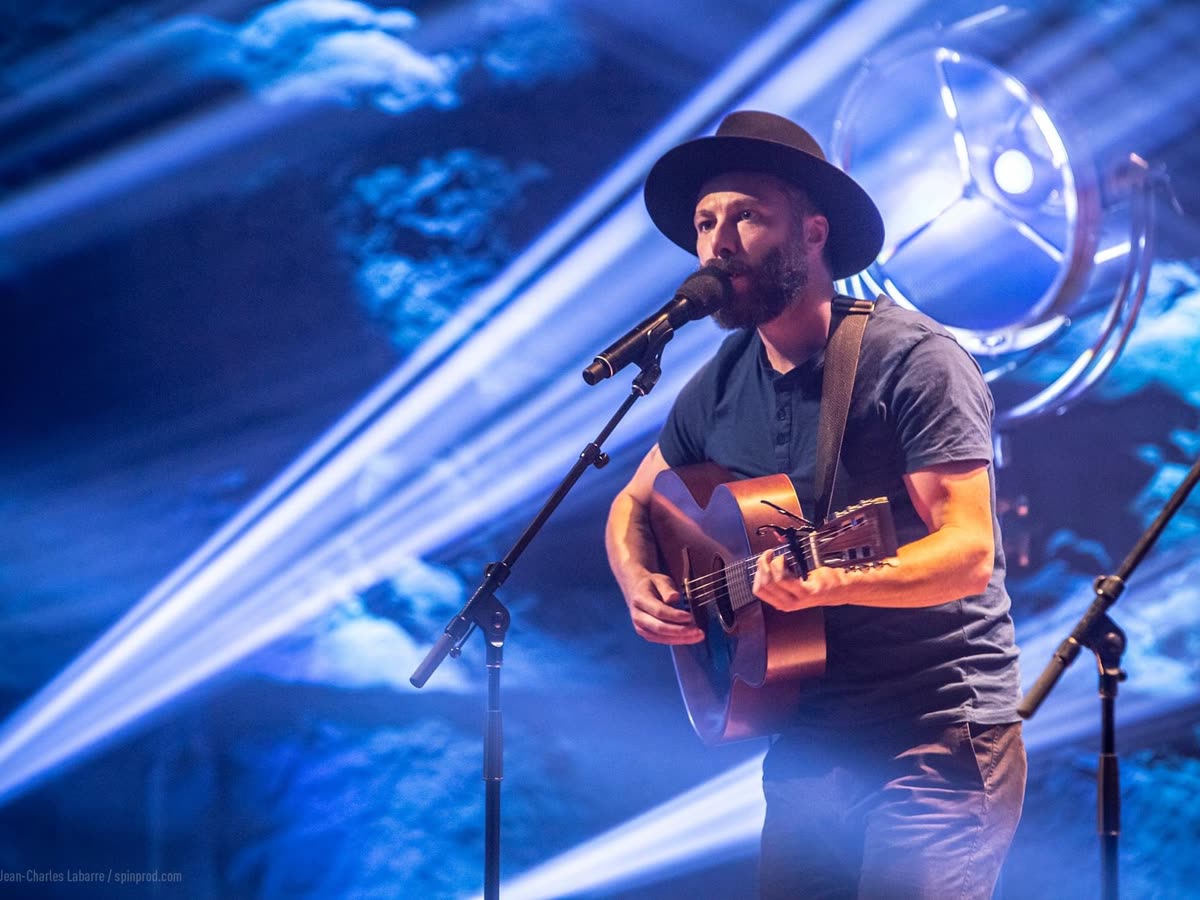 Auteur-compositeur en scène devant des faisceaux bleus rasants, captation télé