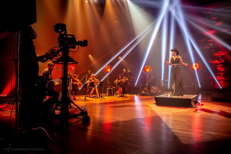 Chanteuse au centre d'un éventail de faisceaux orangés et bleus