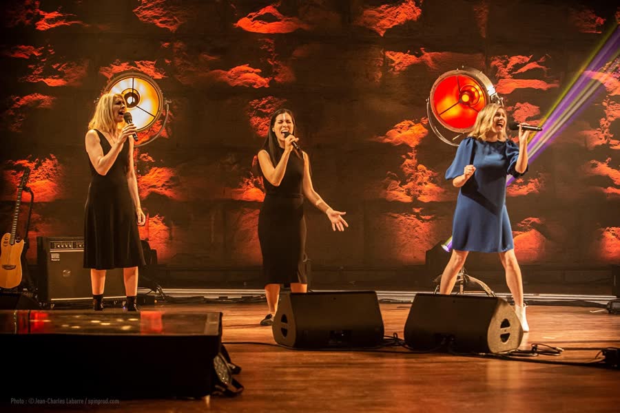 Trio de chanteuses devant des cercles lumineux rouges