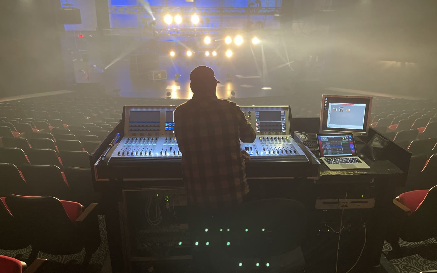 Lighting console facing the stage, crew at the desk during the show